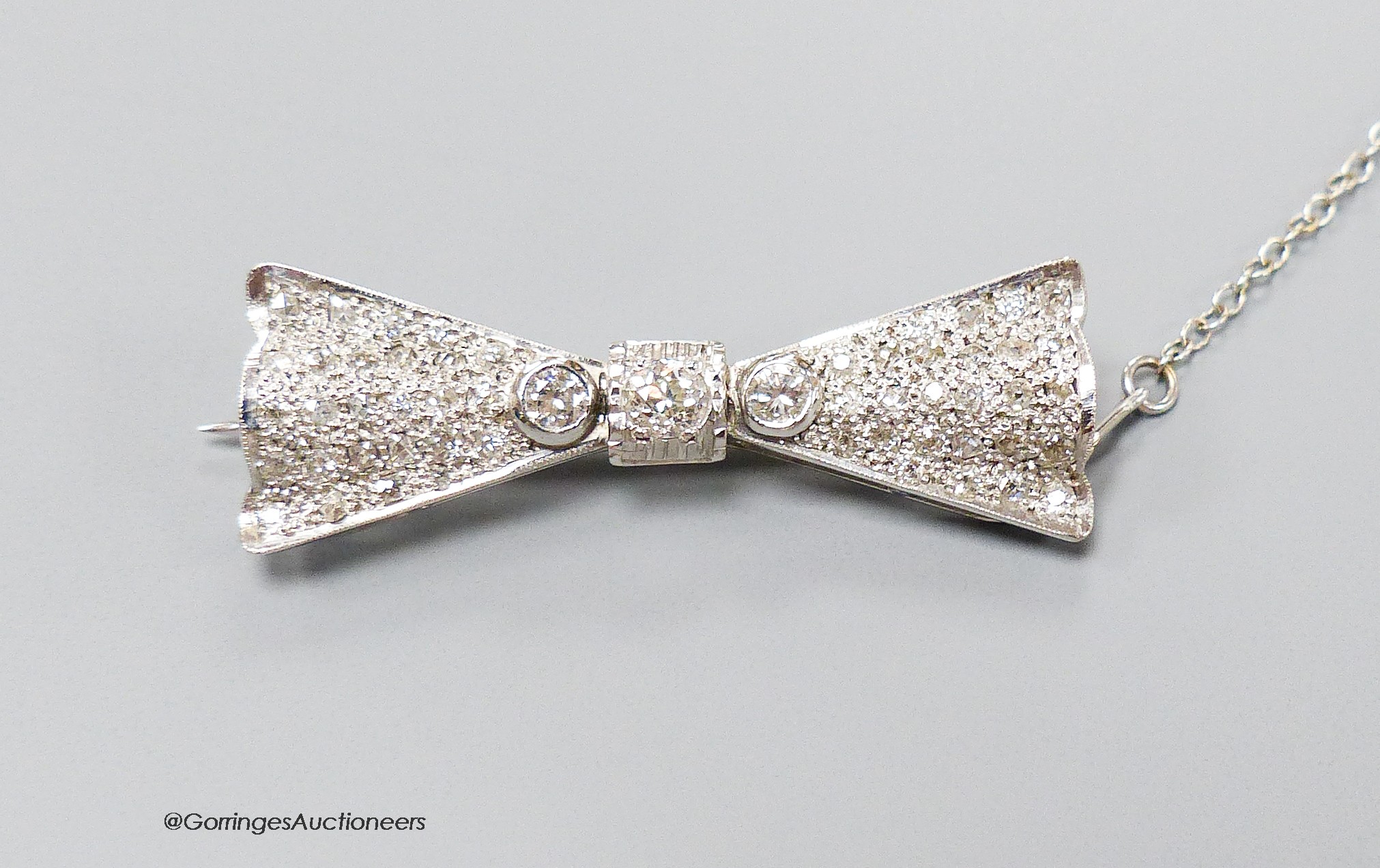 A modern Art Deco style 18ct white gold and diamond encrusted 'bow tie' brooch, 40mm, gross 7.1 grams.